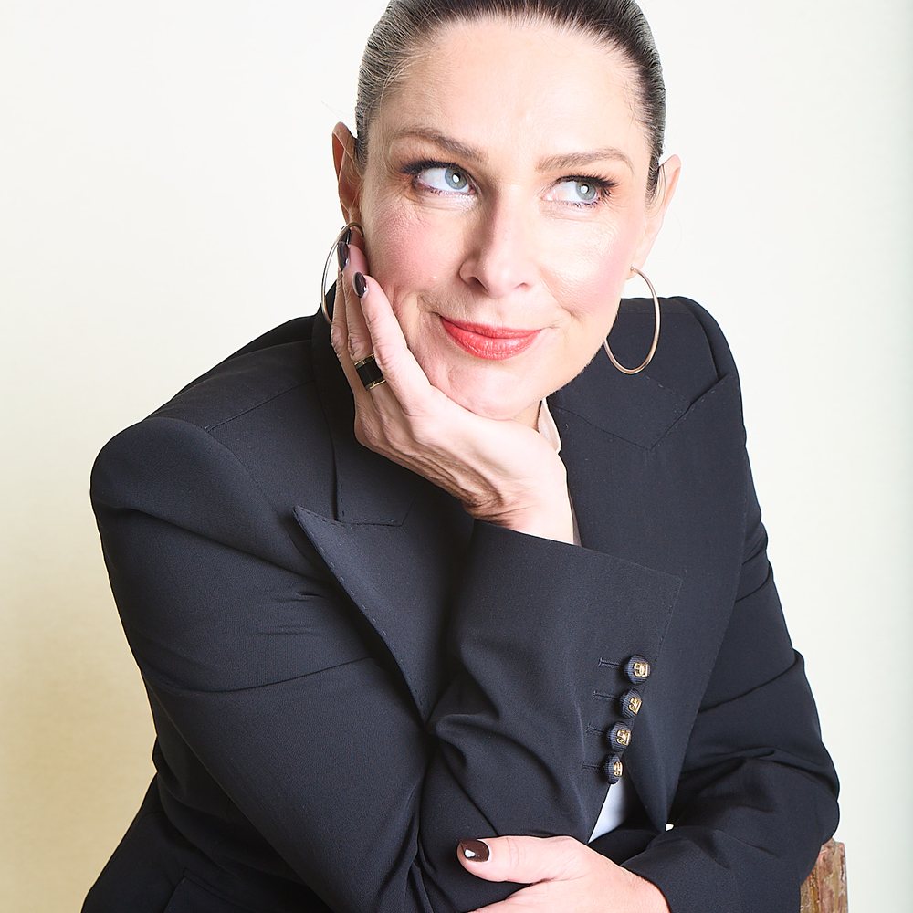 Jacqui Hutton, founder, smiling with her hand to her cheek